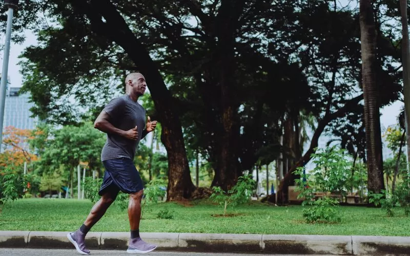 Man running in a running top through a park.