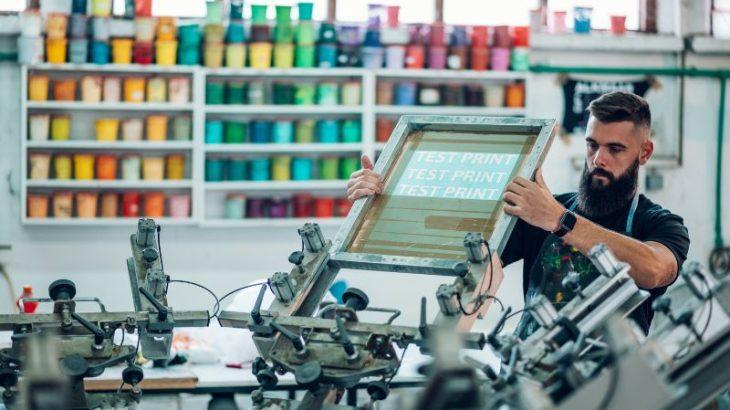 A man setting up a canvas for a test screen print.