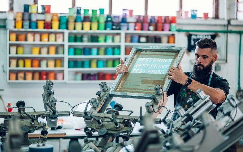 A man setting up a test print on a canvas for screen printing onto a garment.