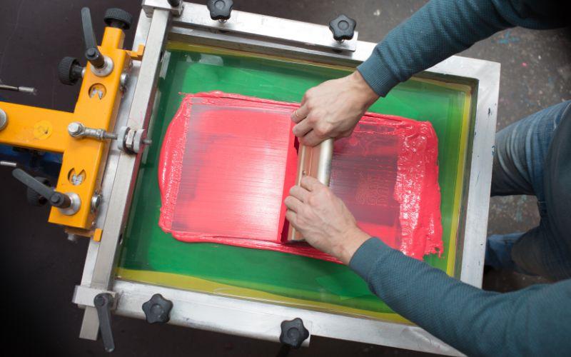 Applying ink to a canvas set up for screen printing.