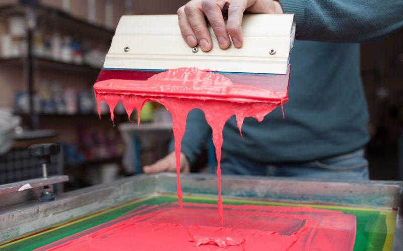 Ink dripping from a tool used for screen printing.