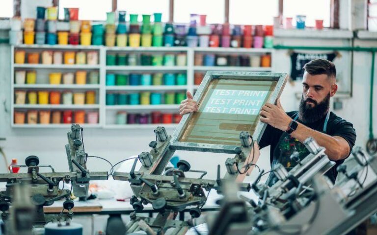 A man setting up a test print on a canvas for screen printing onto a garment.