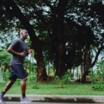 Man running in a running top through a park.
