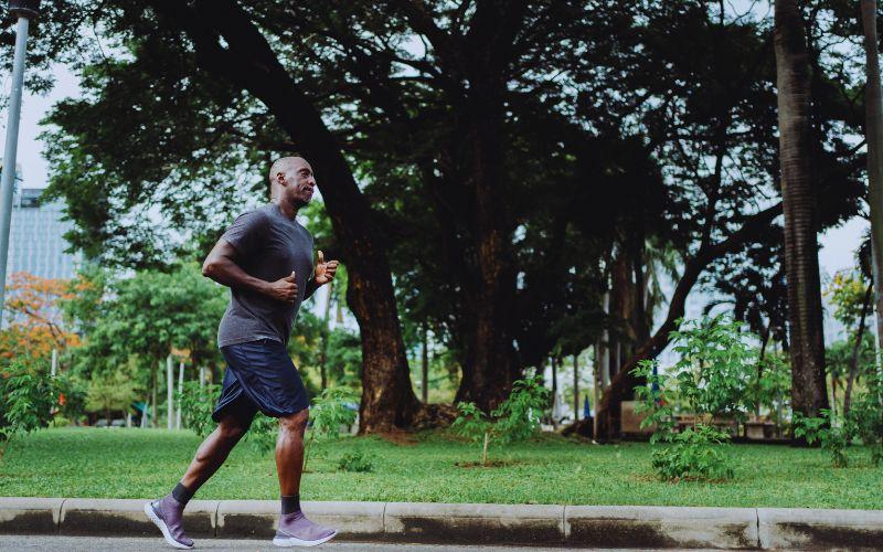 Man running in a running top through a park.